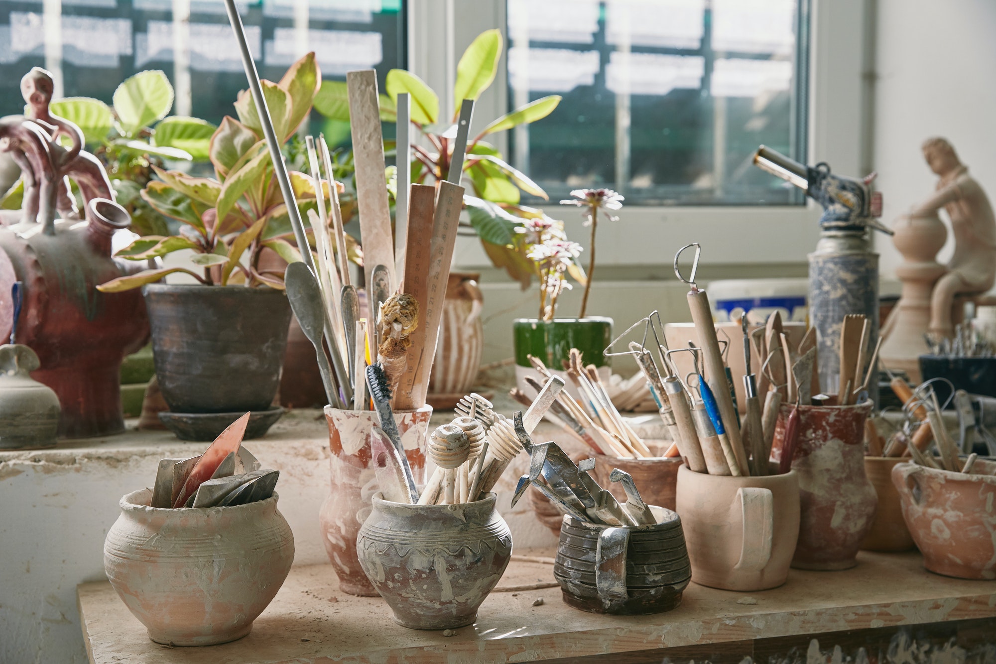selective-focus-of-pottery-tools-and-paintbrushes-at-table-in-pottery-studio.jpg